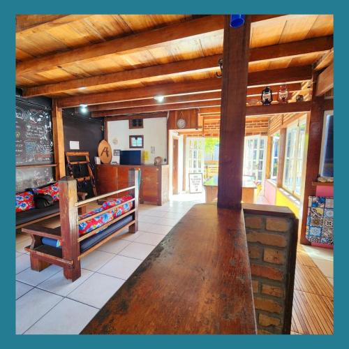a room with a large wooden table in a building at Acquarela Hostel in Arraial do Cabo