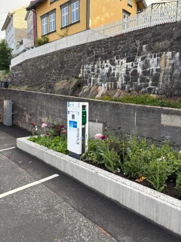 a parking lot with a parking meter next to some plants at Tiny house in Arendal in Arendal