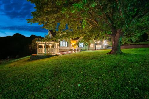 a house with a tree in front of a yard at Luxury Mountain Retreat with Main House and Garage Apartment. Perfect for Families, Retreats and Remote Work in Sparta