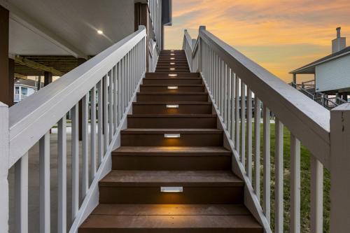 a stairway leading to a house with a sunset in the background at Beach Access Games Firepit Brand New in Bolivar Peninsula