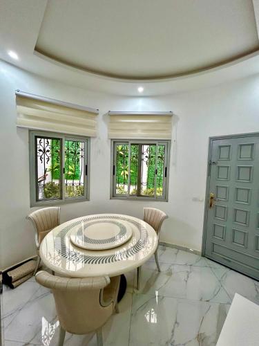 a dining room with a table and chairs and two windows at Pearl Haven Suite - Appartement F2 bord de mer in Dakar