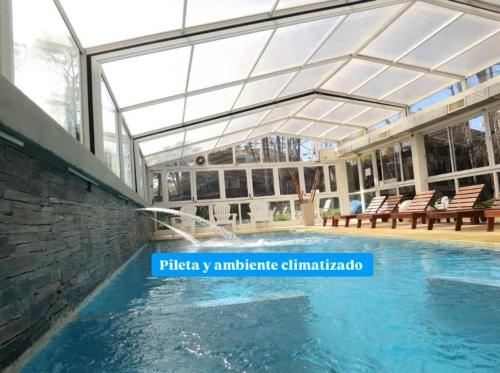 a swimming pool with a building with a glass ceiling at La Posta de Cariló in Carilo