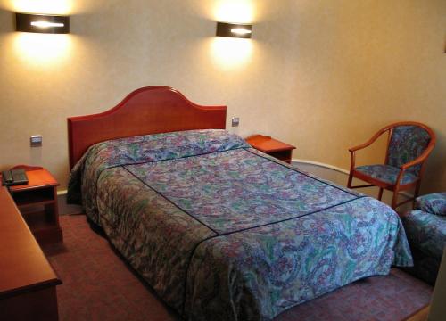 a hotel room with a bed and two chairs at Logis Hotel Restaurant La Croix Verte in Neau