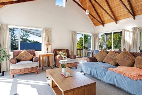 a living room with a blue couch and chairs at Torbay Sun Drenched Villa near Local Beaches in Auckland