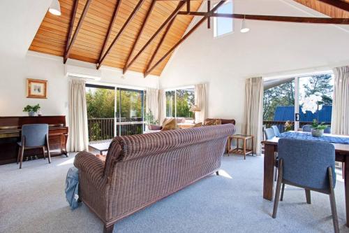 a living room with a couch and a table at Torbay Sun Drenched Villa near Local Beaches in Auckland
