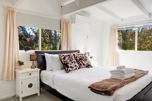 a bedroom with a large white bed with pillows at Torbay Sun Drenched Villa near Local Beaches in Auckland