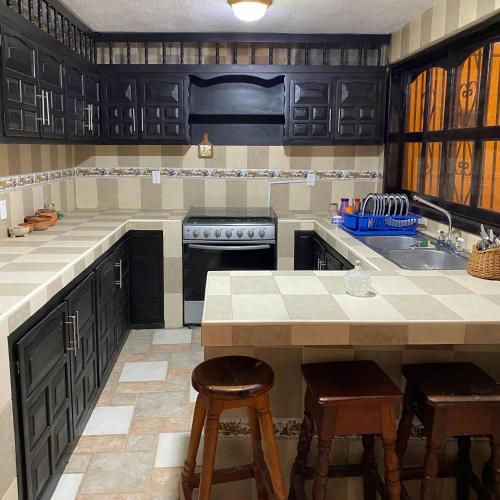 a kitchen with black cabinets and a sink and stools at La casa de la abuela in Palenque