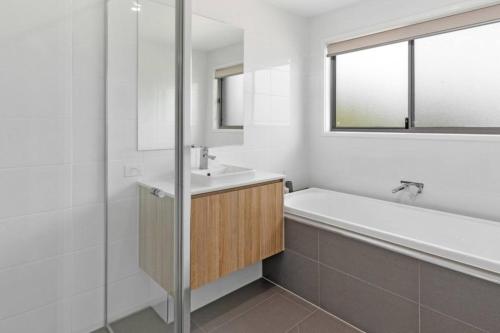 a white bathroom with a tub and a sink and a bath tub at Waterfront Wonderland - Luxury Canal Front Villa w Pool in Gold Coast