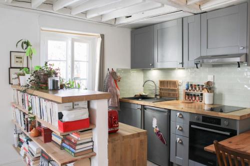 une cuisine avec des armoires grises et une étagère avec des livres dans l'établissement Beautiful studio for couple with courtyard, à Paris