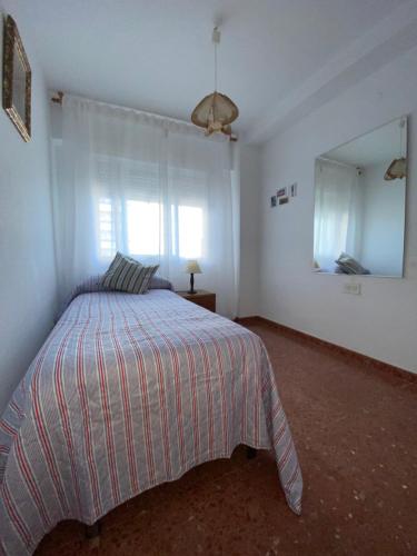 a white bedroom with a bed and a mirror at Brisa y Mar in Punta Umbría