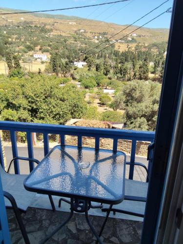 a glass table on a balcony with a view at Andros Guesthouses in Andros