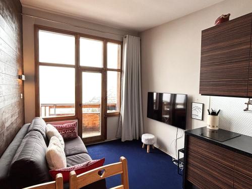 un salon avec un canapé et une grande fenêtre dans l'établissement Bel appart rénové 7ème étage, quartier Falaise, balcon exposé sud, TV, internet, casier à skis - FR-1-634-97, à Morzine