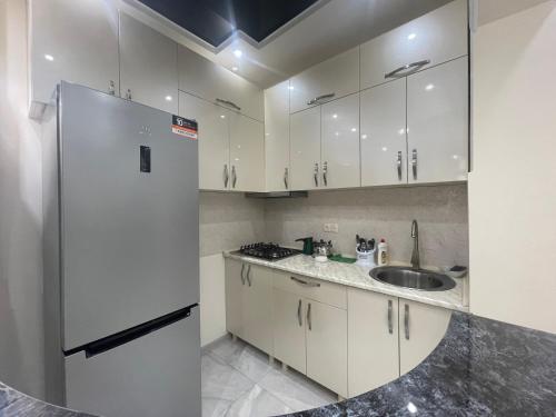 バトゥミにあるETO S Apartment with sea view In Batumiの白いキャビネットと冷蔵庫のあるキッチン