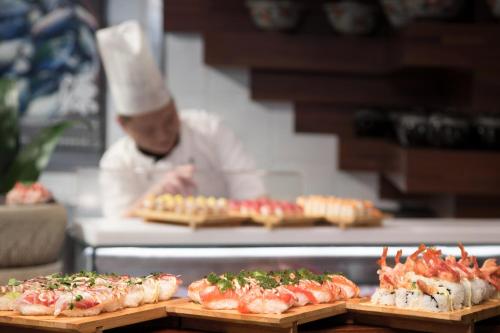 a chef preparing food in a kitchen with sushi at Kerry Hotel Pudong, Shanghai - Indoor Connecting to Shanghai New International Expo Centre in Shanghai