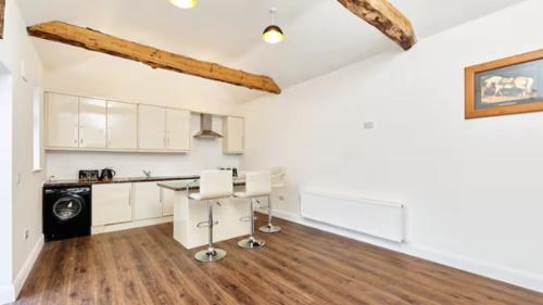a kitchen with white cabinets and a wooden floor at Rushbrooke cottages in Edenderry