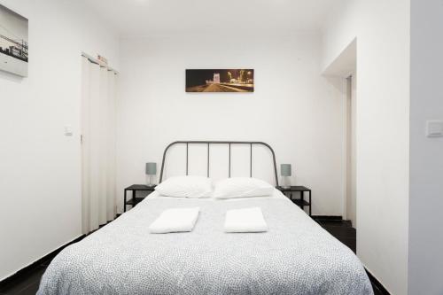 een witte slaapkamer met een bed met 2 witte kussens bij Casa do Pereira in Lissabon