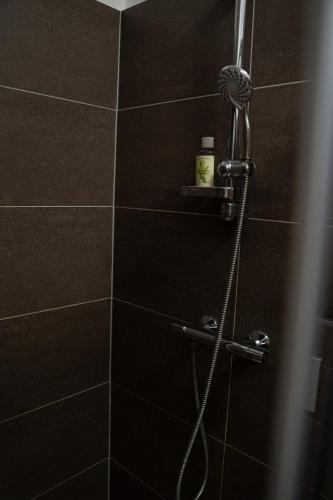 a shower with a hose in a black tiled bathroom at Apartmán na Divoké Desné in Andělské Žleby