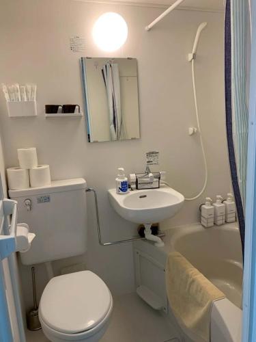 a white bathroom with a toilet and a sink at 新大阪徒步30秒 Shinosaka Station 30s, Direct to Kansai Airport 關西空港直達, Universal Studio 16 mins, Umeda 6 mins, Kyoto 25 mins, Early Check in in Osaka