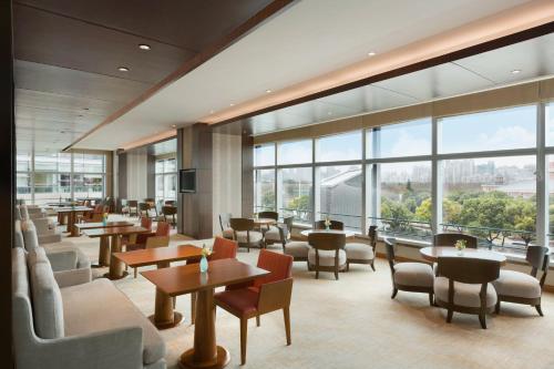 a restaurant with tables and chairs and large windows at Kerry Hotel Pudong, Shanghai - Indoor Connecting to Shanghai New International Expo Centre in Shanghai