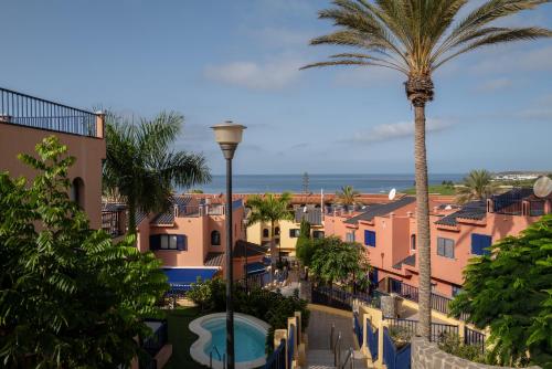 a view of a town with a palm tree and the ocean at Bungalow - Playa Meloneras in San Bartolomé de Tirajana