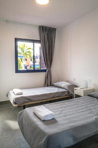 two beds in a room with a window at Bungalow - Playa Meloneras in San Bartolomé