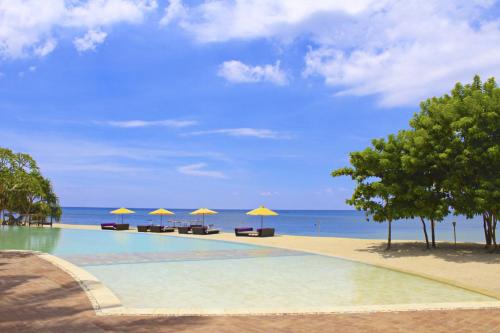 a swimming pool next to a beach with umbrellas at Anema Wellness Villa & Spa Gili Lombok - Diving Center PADI in Tanjung