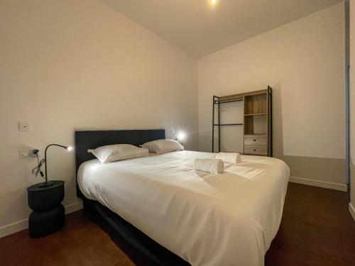 une chambre avec un grand lit blanc avec un miroir dans l'établissement Echappée Paimpolaise, à Paimpol