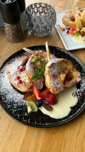 a black plate of food on a wooden table at Deo Plaza Apartments in Gdańsk