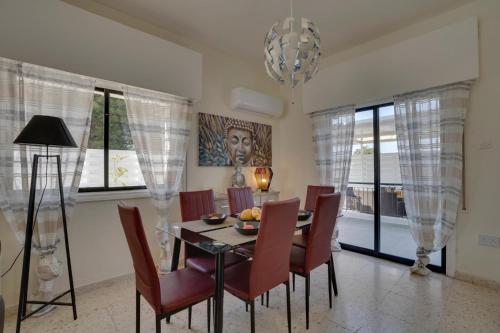 a dining room with a table and chairs and a chandelier at Moments Together Villa in Voroklini