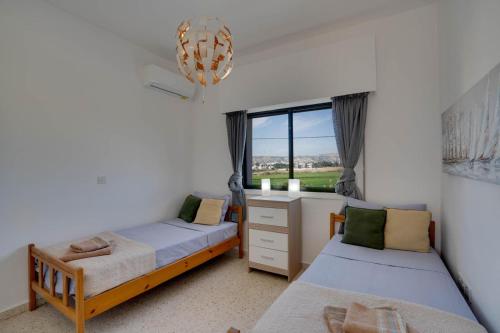 a bedroom with two beds and a desk and a window at Moments Together Villa in Voroklini