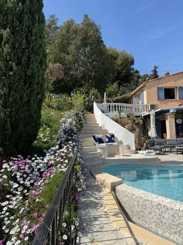une piscine avec des escaliers et des fleurs à côté d'une maison dans l'établissement Villa la Roche Cannes, Meerblick, Salzwasserpool, Sauna, à Mandelieu-la-Napoule