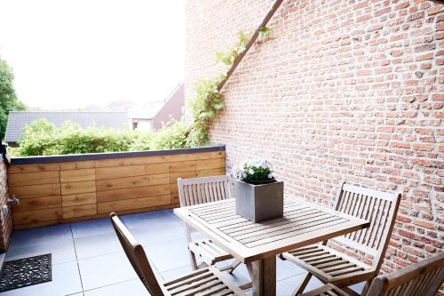 a patio with a table and chairs and a brick wall at Vakantiewoning De Gulden Sleutels in Kruibeke