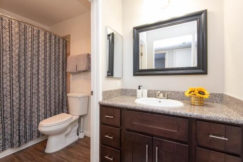 a bathroom with a sink and a toilet and a mirror at Modern Escape in Hollywood with Rooftop & City Views in Los Angeles