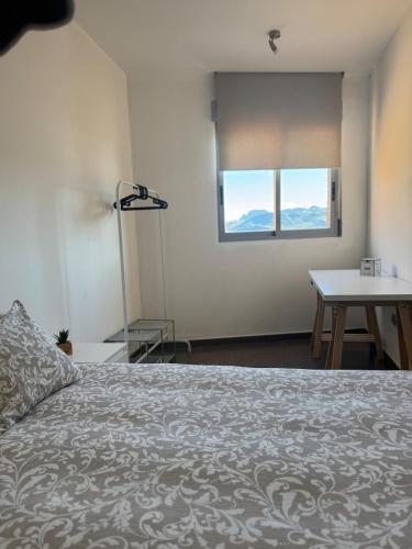 a bedroom with a bed and a table and a window at Ático in Pego