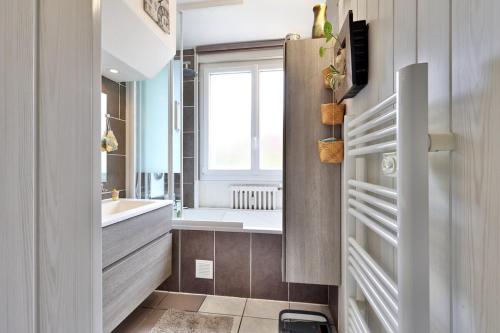 une salle de bain avec une baignoire, un lavabo et une fenêtre dans l'établissement Logement chaleureux avec balcon, à Bron