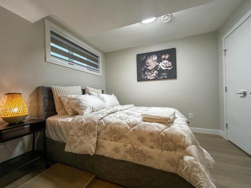 a bedroom with a bed and a lamp and a window at Eli's Place in Calgary