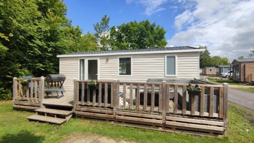 a white tiny house with a wooden fence at MOBILHEIM HERZ LAUWERSOOG - Chalet Schildhoek in Lauwersoog