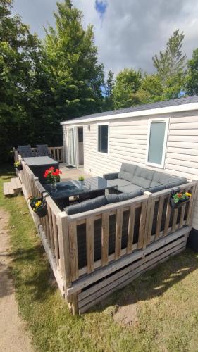 a deck with a couch and chairs on a trailer at MOBILHEIM HERZ LAUWERSOOG - Chalet Schildhoek in Lauwersoog