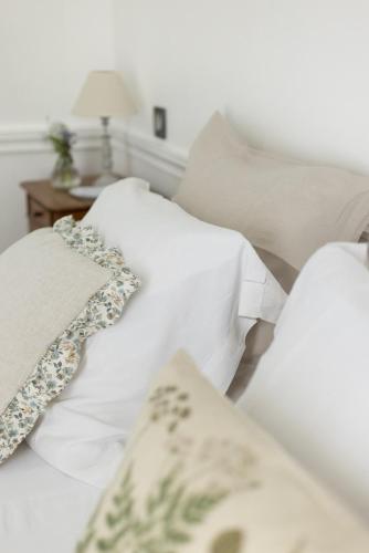 - un lit avec des draps et des oreillers blancs dans l'établissement Le Manoir du Plessis, à Dancé