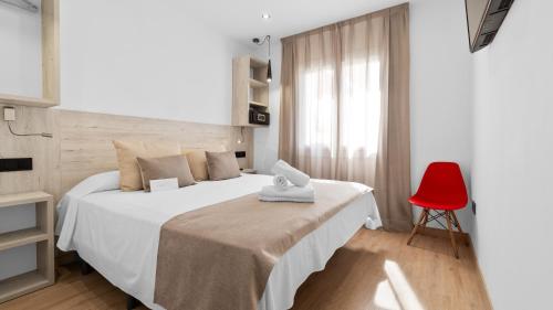a bedroom with a white bed and a red chair at Hotel Costa Brava in Roses