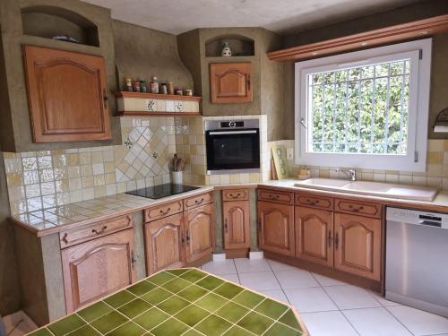 une cuisine avec des armoires en bois et une fenêtre dans l'établissement Villa au pied d'une colline, à La Farlède