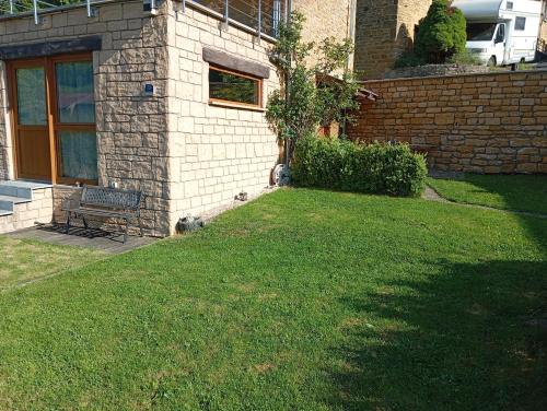 a yard with a bench in front of a house at Le cabanon au bord de l'Othain in Bazeilles-sur-Othain