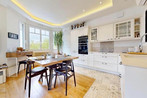 une cuisine avec des armoires blanches et une table et des chaises en bois dans l'établissement Le Chapuisien - 4 étoiles vielle ville et lac, à Annecy