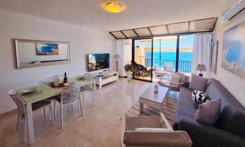 a living room with a couch and a table at Seafront apartment Terrace, lounger & Panoramic ocean views in Mellieħa