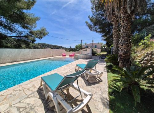 - une piscine avec 2 chaises et un palmier dans l'établissement La Bergerie, maison T3 avec Piscine, à Sanary-sur-Mer