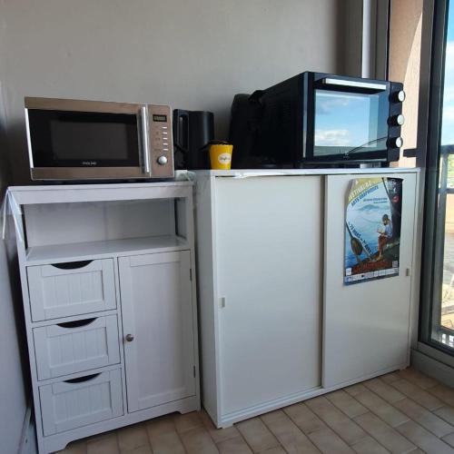 un micro-ondes posé sur une armoire blanche avec un micro-ondes dans l'établissement Charmant 2 pièces, Vue sur Mer - Proche Plage, à Sète