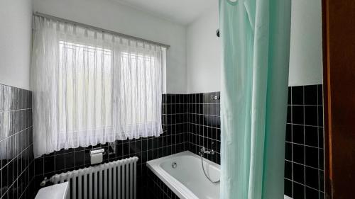 a black and white bathroom with a tub and a window at Ca' Cagiallo - Apartment in Capriasca in Tesserete