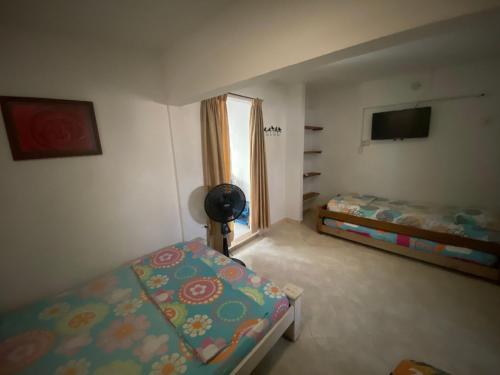a bedroom with two beds and a television in it at Casa de Playa Manecal in Coveñas
