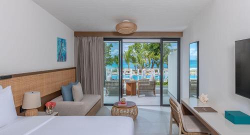 a hotel room with a bed and a living room at Avani+ Barbarons Seychelles in Grand'Anse