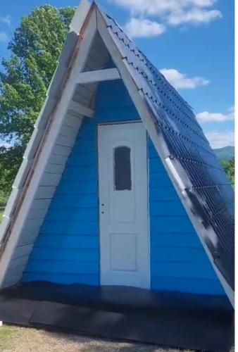 a blue house with a white door in a field at Carul cu Stele-Glamping in Romîneşti